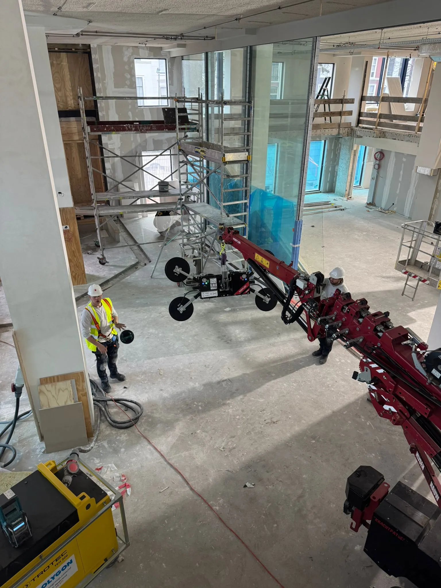 Glaszetters plaatsen grote ruit met Rotec kraanarm en Viavac glaszuiger op bouwplaats